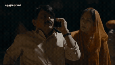 A Man Talking On A Cell Phone Next To A Woman With Ayee Sasur Written In White GIF