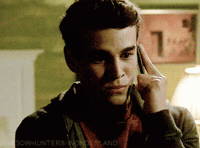 A Man Talking On A Cell Phone With A Sign In The Background That Says 1 GIF