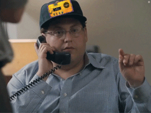 A Man Talking On A Phone With A Patch On His Hat That Says ' Texas ' On It GIF