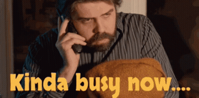 A Man Talking On A Phone With The Words Kinda Busy Now Written Below Him GIF
