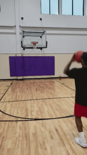 A Man Throws A Basketball In A Gym With A Purple Mat GIF