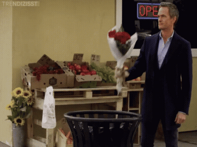 A Man Throws A Bouquet Of Roses Into A Trash Can In Front Of A Store That Is Open GIF