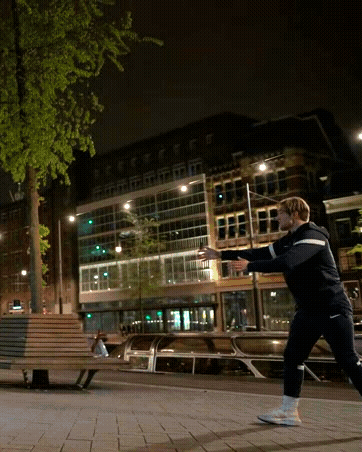 A Man Throws A Frisbee In A City At Night GIF