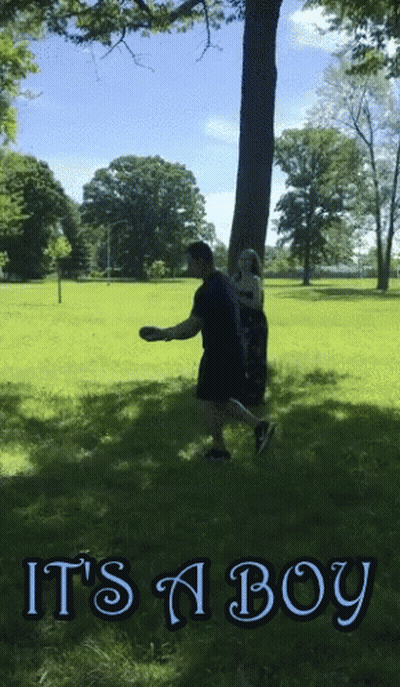 A Man Throws A Frisbee In A Park With The Words It 'S A Boy GIF