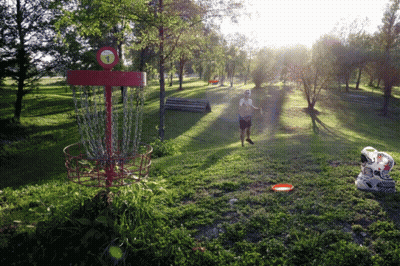 A Man Throws A Frisbee Into A Red Frisbee Golf Basket GIF