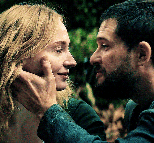 A Man Touches A Woman 'S Face While They Look At Each Other GIF