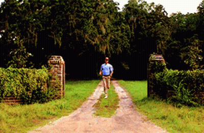 A Man Walking Down A Dirt Road In A Field GIF