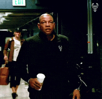 A Man Walking Down A Hallway With An Exit Sign On The Wall GIF