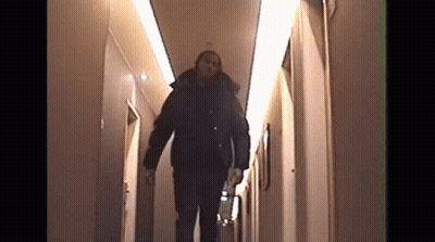 A Man Walking Down A Hallway With The Number 10 On The Wall Behind Him GIF