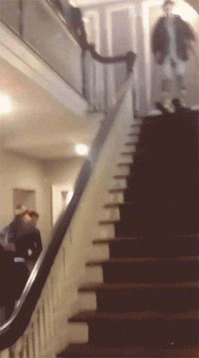 A Man Walking Down A Set Of Stairs In A House GIF