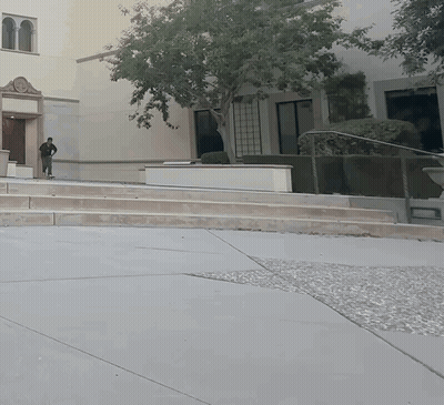 A Man Walking Down A Set Of Stairs In Front Of A Large Building GIF