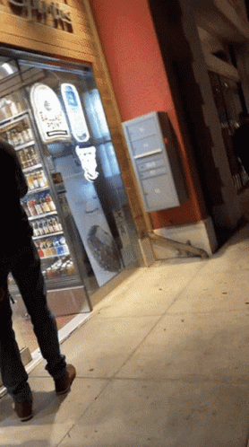 A Man Walking Down A Sidewalk In Front Of A Store That Says ' Ice Cream ' On It GIF