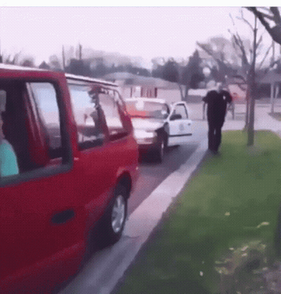 A Man Walking Down A Sidewalk Next To A Red Van GIF