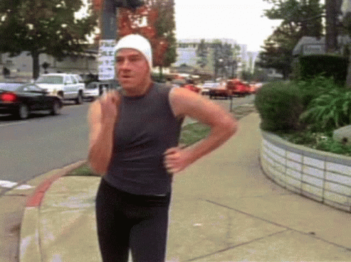 A Man Walking Down A Sidewalk With A Sign That Says " No Parking " GIF