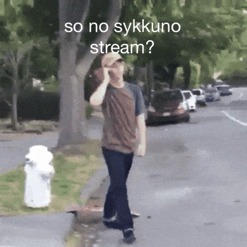 A Man Walking Down A Street Talking On A Cell Phone With The Words So No Sykkuno Stream Below Him GIF