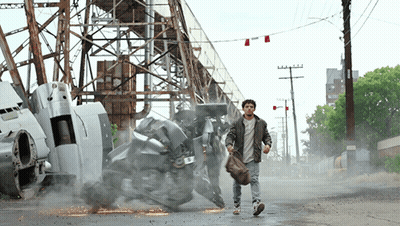 A Man Walking Down A Street With A Robot In The Background And A Sign That Says ' A.m. ' On It GIF