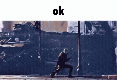 A Man Walking Down A Street With The Word Ok On The Bottom GIF