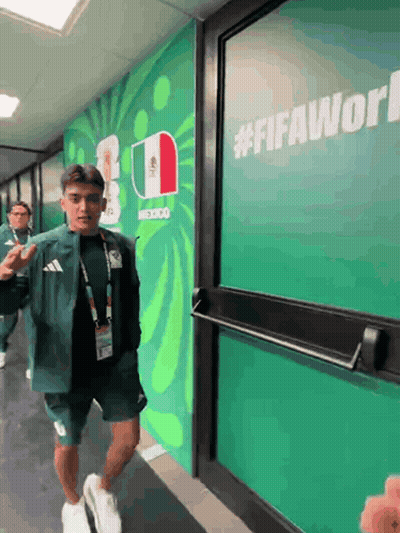 A Man Walking In A Hallway With A Sign That Says #Fifaworld On It GIF