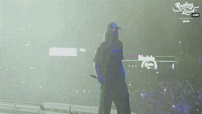 A Man Walking On A Stage With Rolling Loud Written On The Bottom GIF