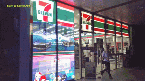 A Man Walks Past A 7 Eleven Convenience Store GIF