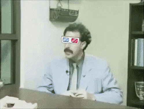 A Man Wearing 3D Glasses Sits At A Table GIF