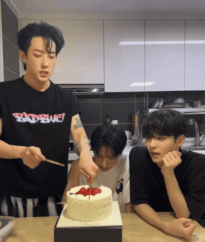 A Man Wearing A Badboy Shirt Is Cutting A Birthday Cake GIF