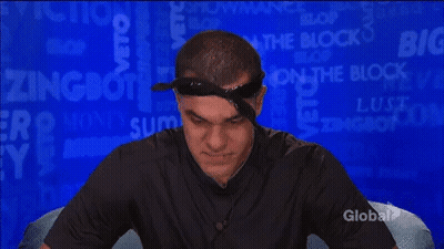 A Man Wearing A Bandana And A Black Shirt Is Sitting In Front Of A Blue Background With The Word Block On It . GIF