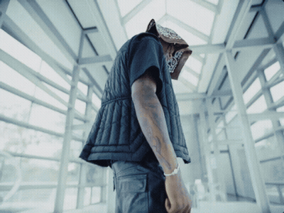 A Man Wearing A Bandana And A Black Vest Looks Down GIF