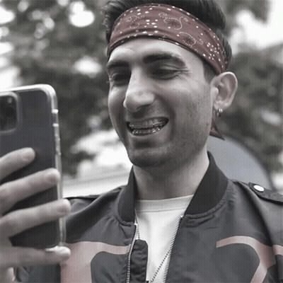 A Man Wearing A Bandana And Braces Takes A Selfie With His Phone GIF