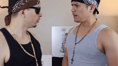A Man Wearing A Bandana And Sunglasses Talks To Another Man Wearing A Rosary Necklace GIF