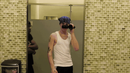 A Man Wearing A Bandana Taking A Picture Of Himself In A Bathroom Mirror GIF