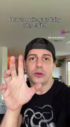 A Man Wearing A Baseball Cap And A Black T-Shirt Is Making A Hand Gesture . GIF