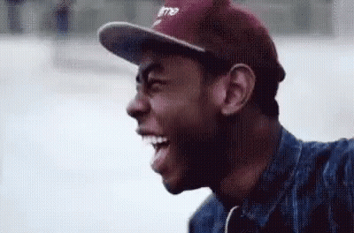 A Man Wearing A Baseball Cap And A Denim Jacket Is Smiling . GIF