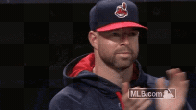 A Man Wearing A Baseball Cap And A Hoodie Is Clapping His Hands . GIF