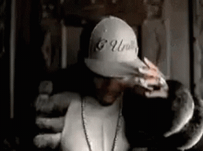 A Man Wearing A Baseball Cap And A Necklace Is Holding A Snake . GIF