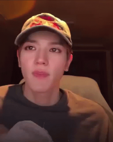 A Man Wearing A Baseball Cap And A Sweatshirt Is Sitting In A Car . GIF