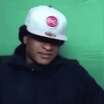 A Man Wearing A Baseball Cap And Sunglasses Is Making A Funny Face . GIF