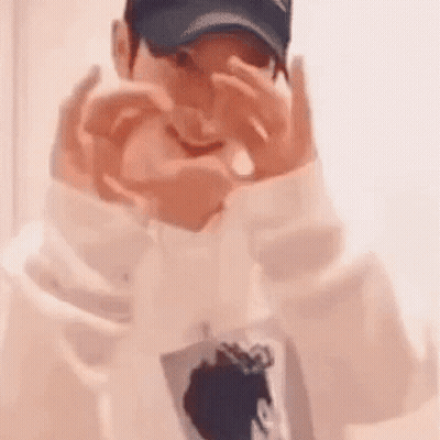 A Man Wearing A Baseball Cap Is Making A Heart With His Hands . GIF