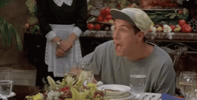 A Man Wearing A Baseball Cap Is Sitting At A Table With Plates Of Food And Glasses Of Water . GIF