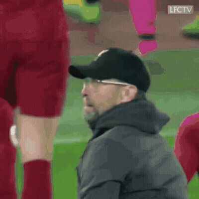 A Man Wearing A Baseball Cap Is Sitting On The Sidelines Of A Soccer Game . GIF