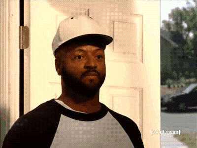 A Man Wearing A Baseball Cap Is Standing In Front Of A Door That Has Adult Swim Written On It GIF