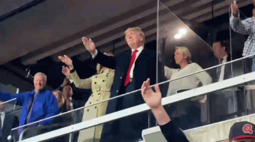 A Man Wearing A Baseball Cap With The Letter A On It Stands In A Crowd GIF