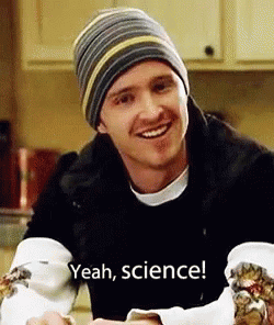 A Man Wearing A Beanie And A Black Jacket Is Smiling And Holding A Piece Of Food . GIF