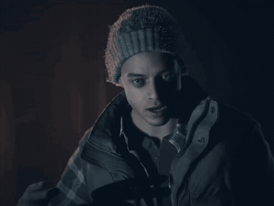 A Man Wearing A Beanie And A Jacket Is Giving The Peace Sign GIF