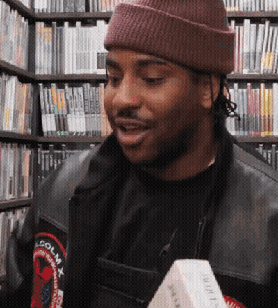 A Man Wearing A Beanie And A Jacket That Says Lcolmx GIF