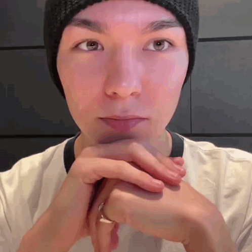A Man Wearing A Beanie And A Ring Is Looking At The Camera . GIF