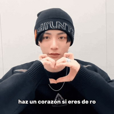 A Man Wearing A Beanie And A Sweater Makes A Heart Shape With His Hands GIF