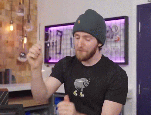 A Man Wearing A Beanie And A T-Shirt With A Camera On It GIF