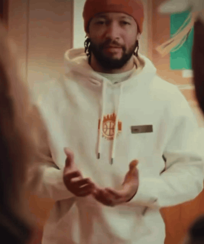 A Man Wearing A Beanie And A White Hoodie With The Letter B On The Front GIF