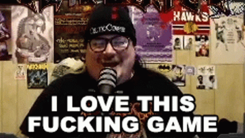 A Man Wearing A Beanie And Glasses Is Talking Into A Microphone And Says I Love This Fucking Game . GIF